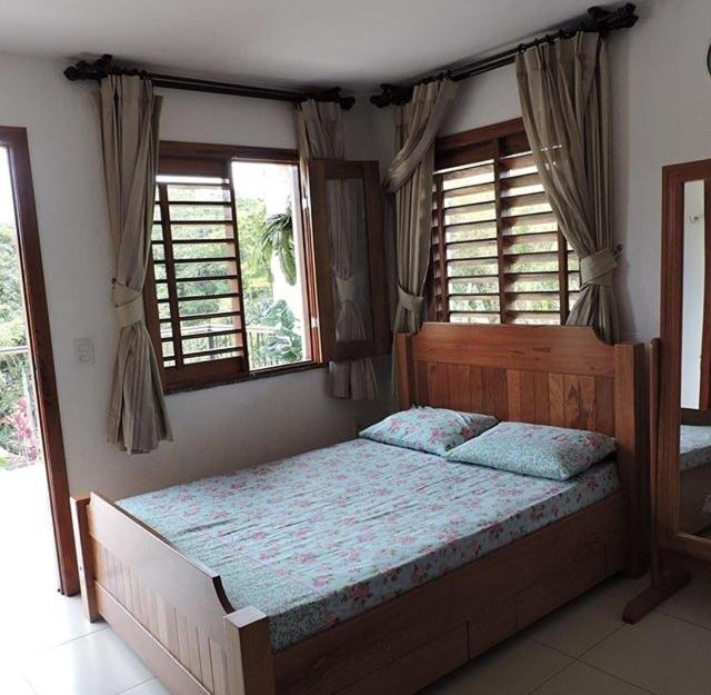 a bedroom with a bed in a room with windows at TRIPLEX SOLAR CASA BRANCA in Guaramiranga