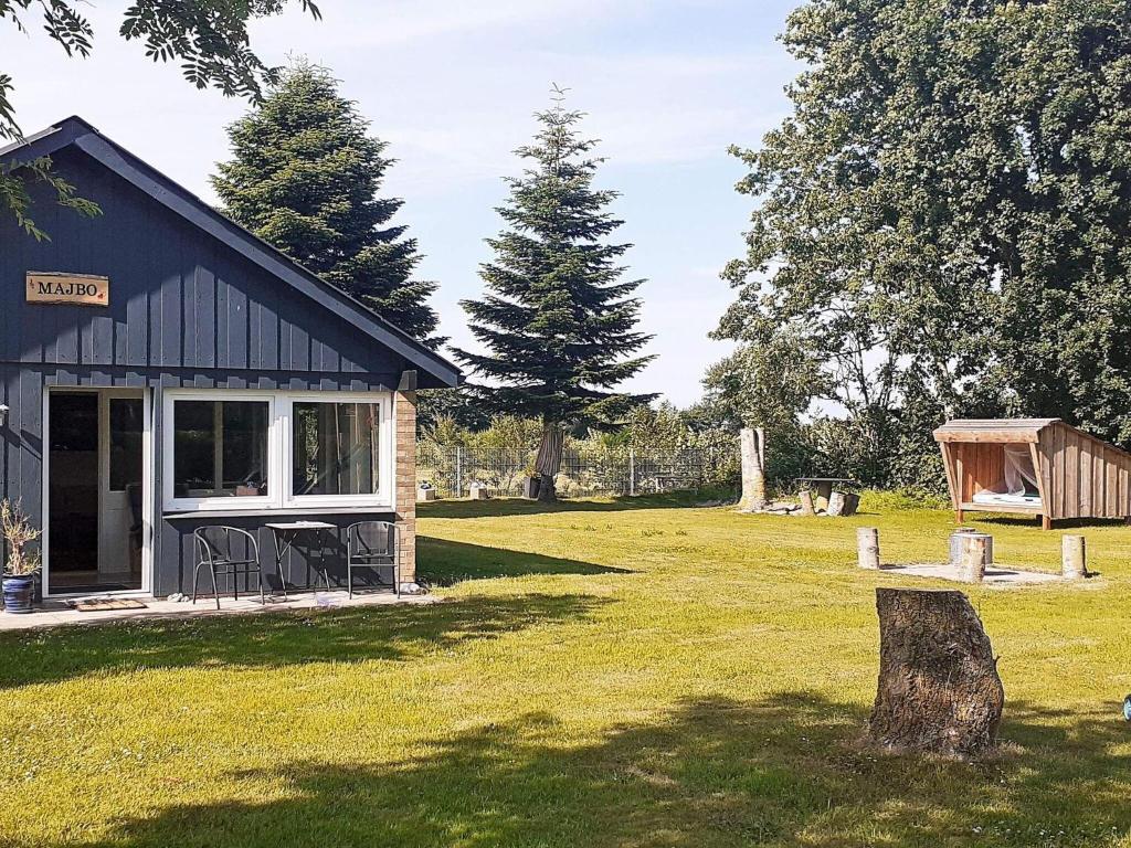 a cabin in a field with a tree stump at Holiday home Nordborg XIII in Nordborg