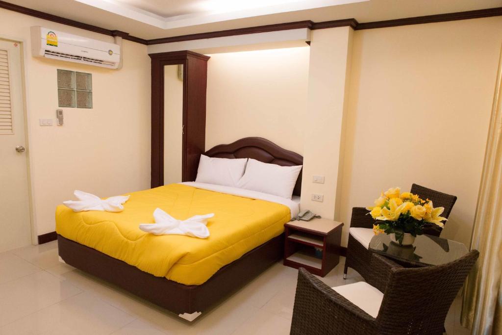 a bedroom with a bed with yellow sheets and flowers at Honey House 3 in Jomtien Beach
