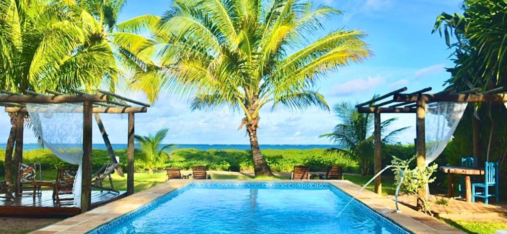 una piscina con palmeras y vistas al océano en Pousada do Sonho, en São Miguel dos Milagres