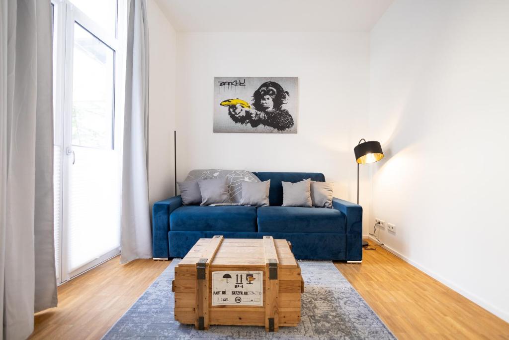 a living room with a blue couch and a coffee table at Ko-Living - Beatles und Banksy Suites & Studios am Eselsbrunnen - Altstadt - Küche in Halle an der Saale