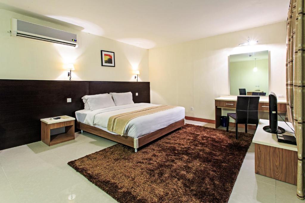 1 dormitorio con cama, escritorio y espejo en The Orchard Cebu Hotel & Suites, en Cebú