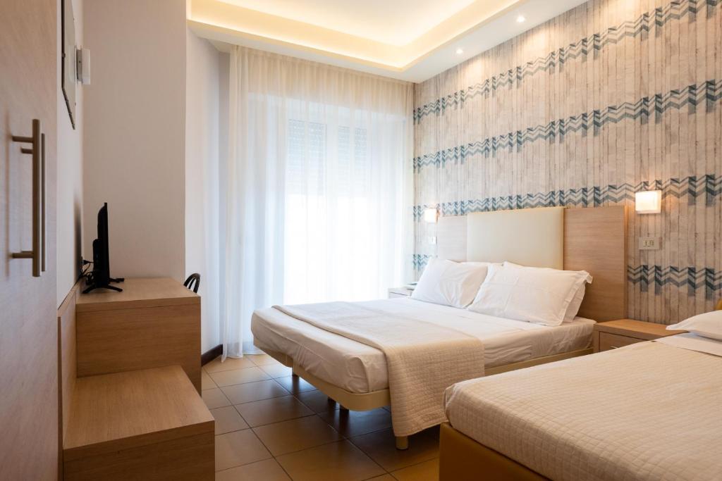 a hotel room with two beds and a window at Hotel City in Rimini