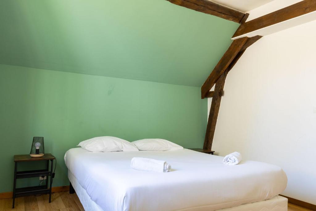 a white bed in a room with a green wall at Cacatoès in Saint-Aignan