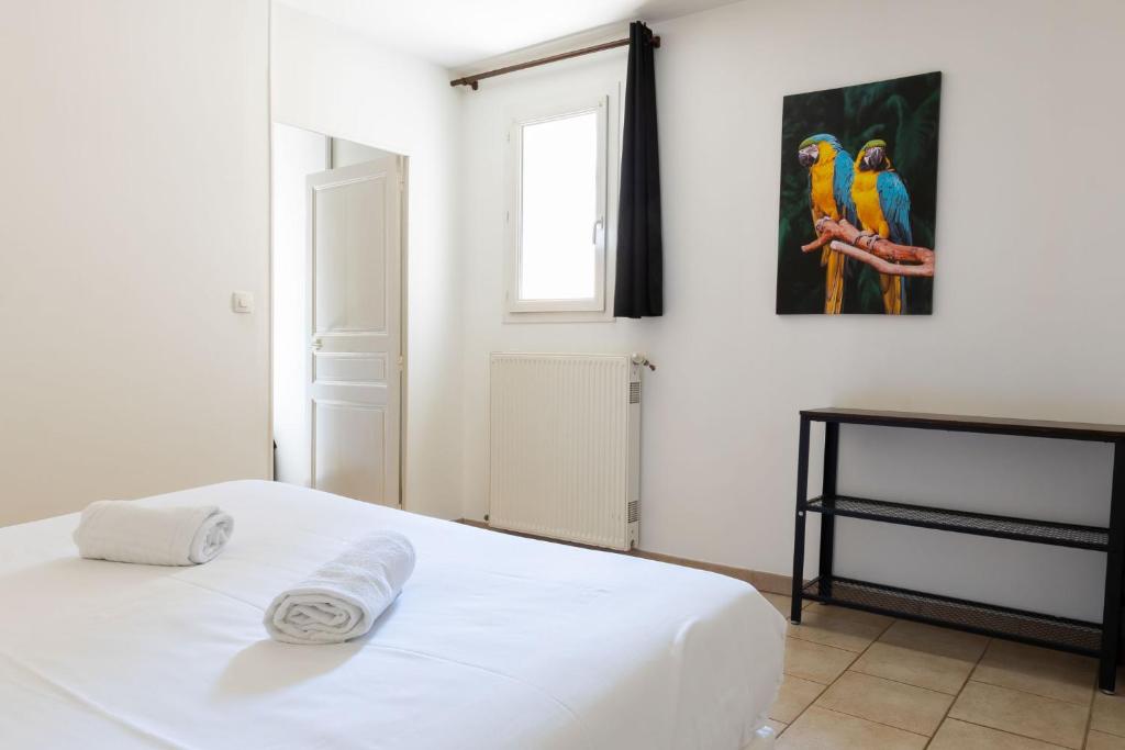 a bedroom with a white bed and a painting on the wall at Cacatoès in Saint-Aignan