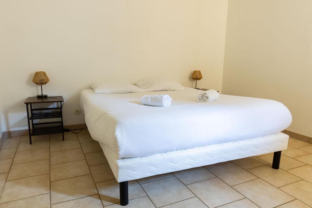 a bedroom with a white bed with two towels on it at Cacatoès in Saint-Aignan