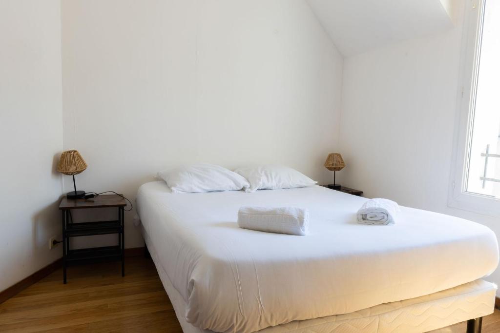 a bedroom with a white bed with two towels on it at Cacatoès in Saint-Aignan