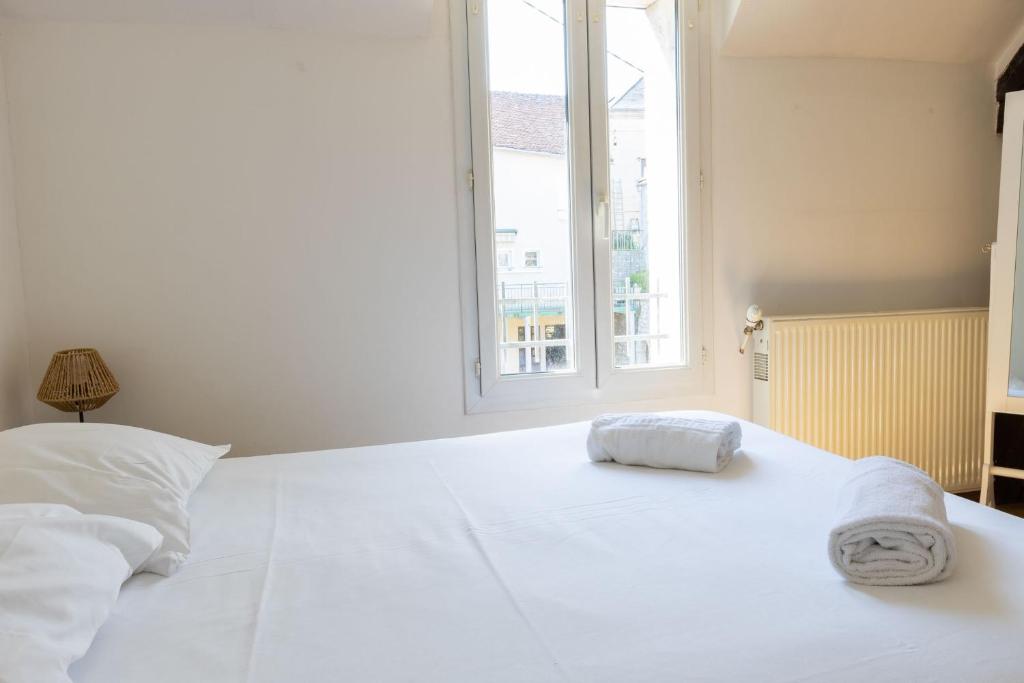 a white bed in a room with a window at Cacatoès in Saint-Aignan