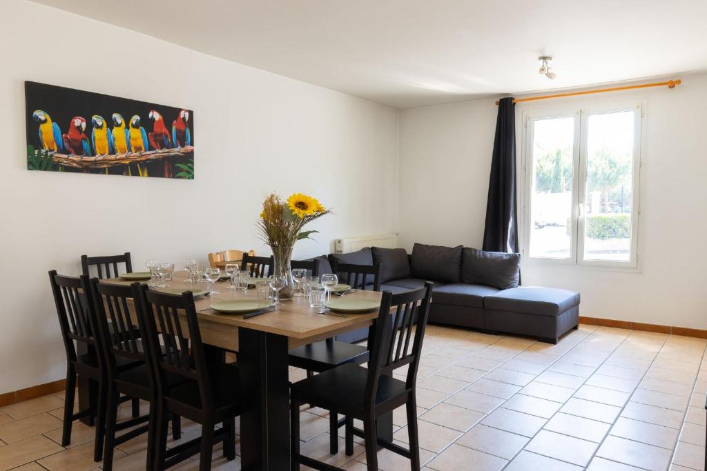 a dining room with a table and a couch at Cacatoès in Saint-Aignan