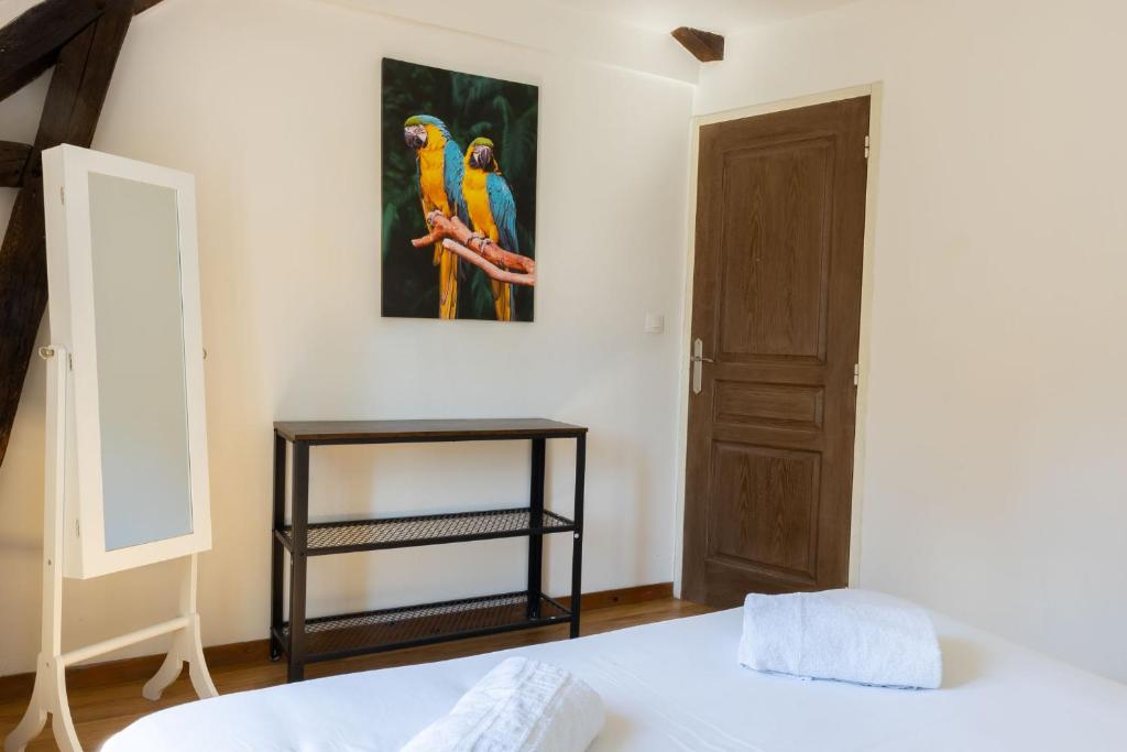 a bedroom with a bed and a picture of parrots on the wall at Cacatoès in Saint-Aignan