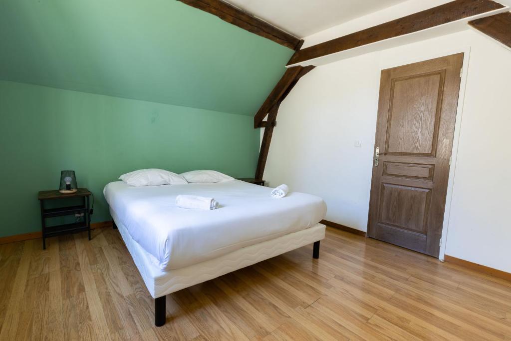 a bedroom with a white bed and a wooden floor at Cacatoès in Saint-Aignan