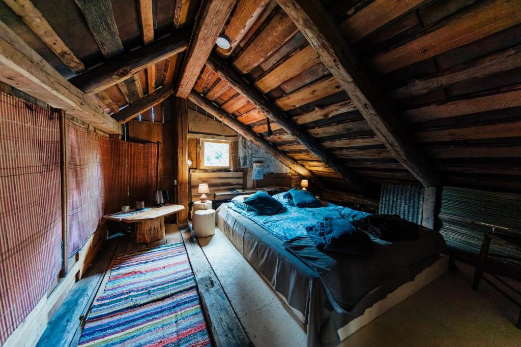 a bedroom with a large bed and a wooden ceiling at Pilsētas glempings - "Šķūņaugša" in Valmiera