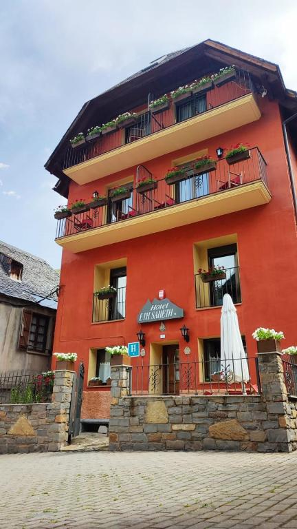 un edificio arancione con un ombrello bianco davanti di Hotel Saueth a Tredós