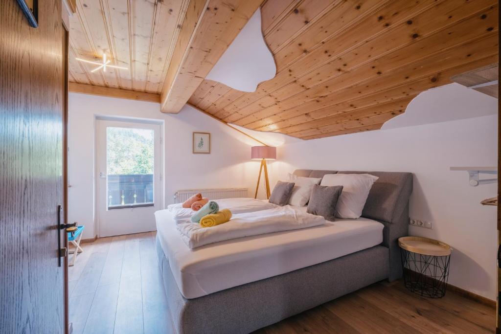 a bedroom with a large white bed and wooden ceilings at Kaiser Apartments in Scheffau am Wilden Kaiser