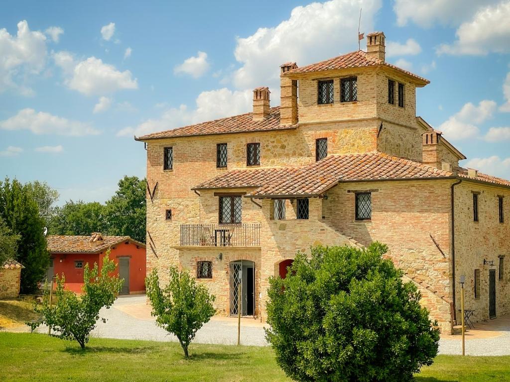 un grande edificio in mattoni con una torre sopra di Villaluce Wine Agriturismo a Castiglione del Lago