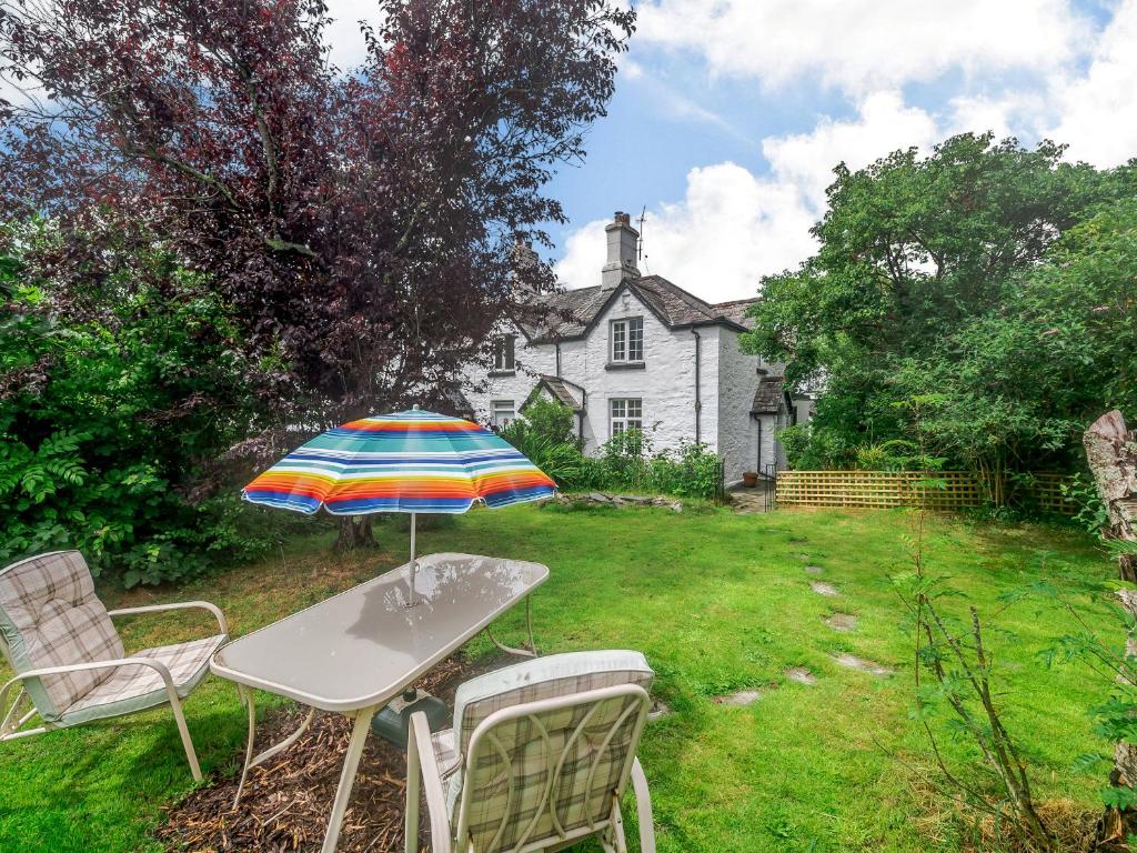 a table and chairs with an umbrella in front of a house at Bluebell Cottage in Tavistock