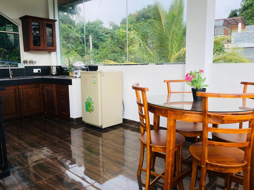 Kandy River Garden في كاندي: مطبخ مع طاولة وكراسي وثلاجة