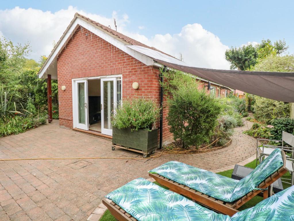 a brick house with a patio and some chairs at Birch Cottage in Norwich
