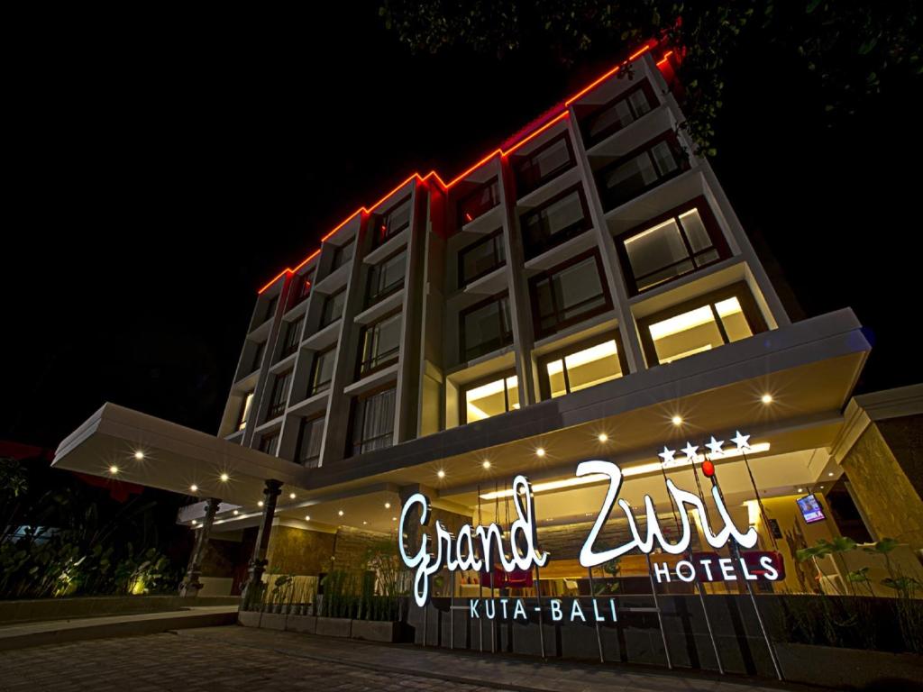 un hotel con un cartel delante de él por la noche en Grand Zuri Kuta Bali, en Kuta