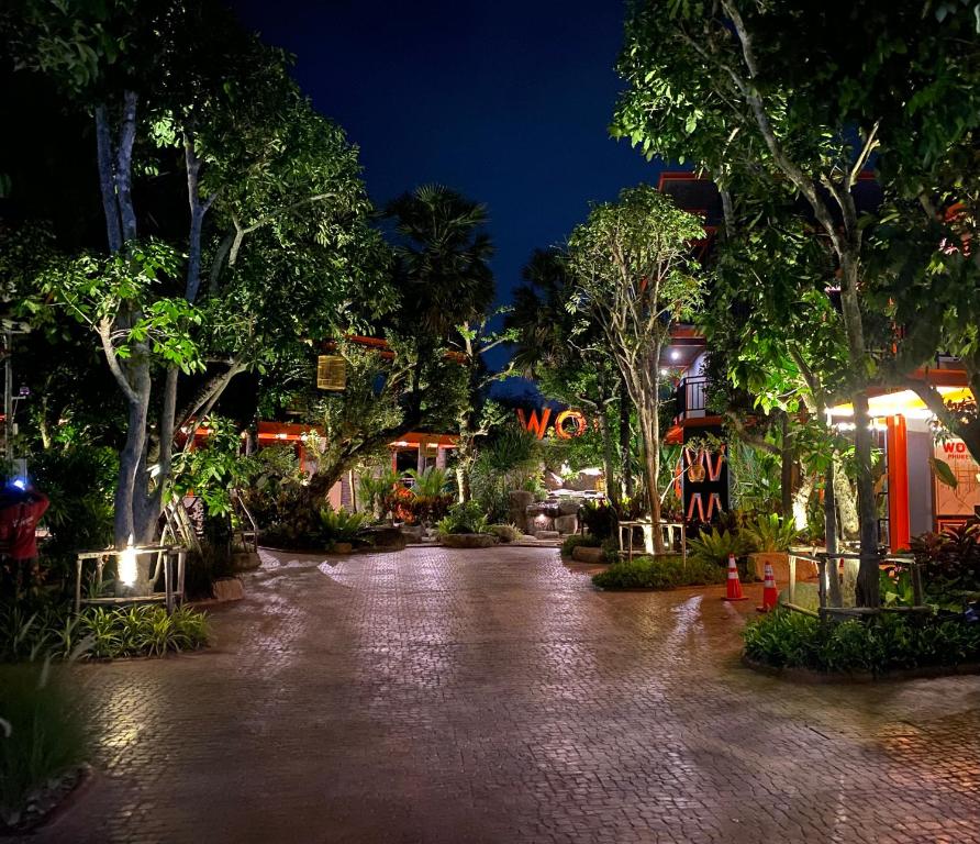 una pasarela por la noche con árboles y letreros de neón en WOW PHUKET, en Phuket