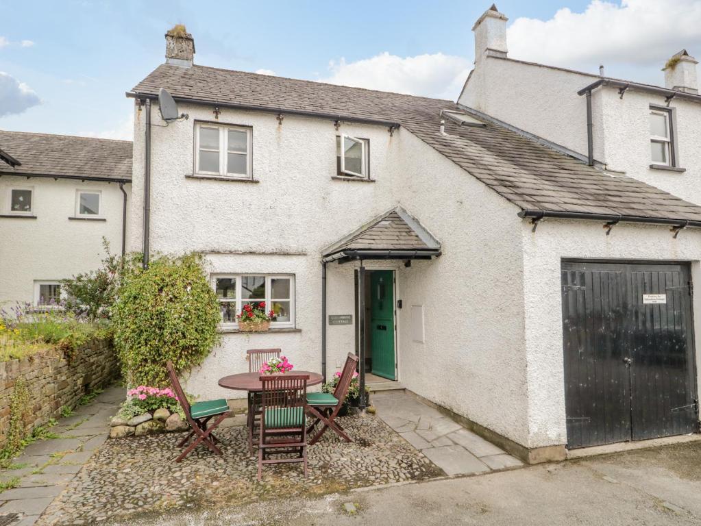 a white house with a table and chairs in front of it at Columbine Cottage in Ambleside
