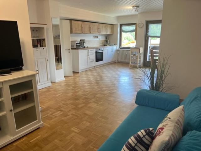 a living room with a blue couch and a kitchen at Apartment Wendelsteinblick - Wohnen auf Zeit - Homeoffice - Balkon mit Bergblick- buchbar ab 28 Nächte in Schliersee