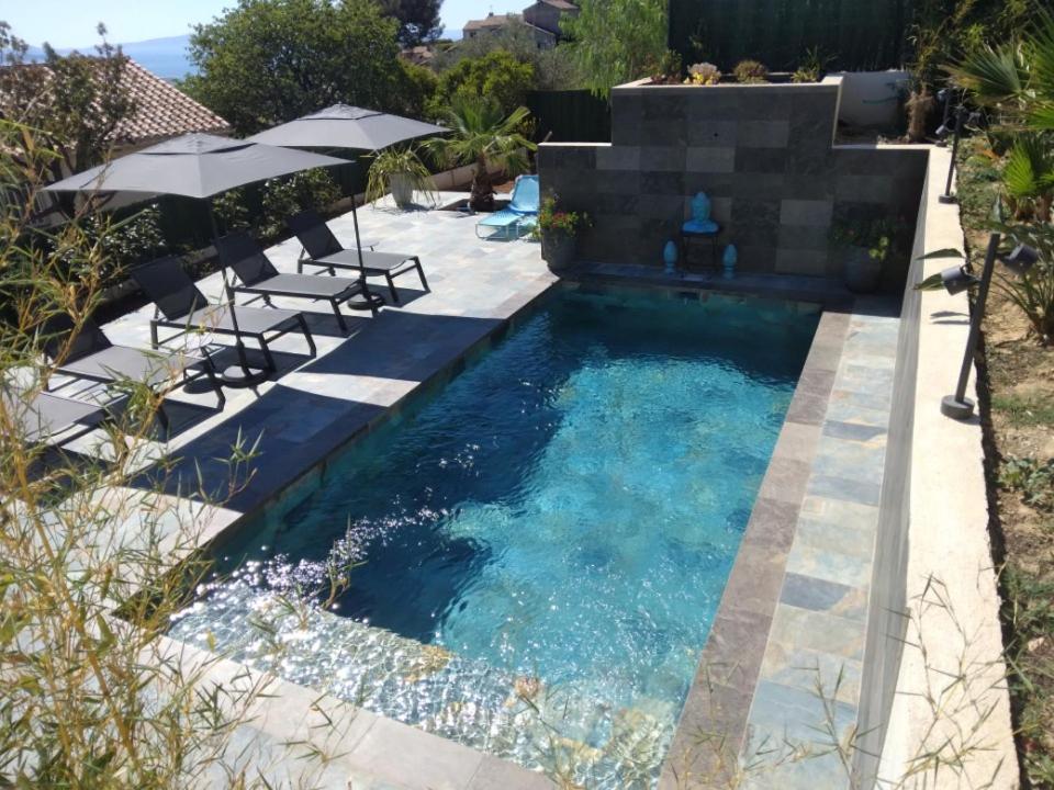 a pool with chairs and umbrellas in a backyard at Le Spot 577 in La Ciotat