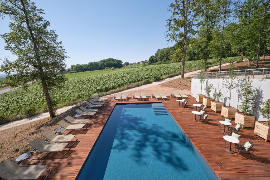 een zwembad met stoelen en tafels en een wijngaard bij LOISIUM Wine & Spa Hotel Champagne in Mutigny