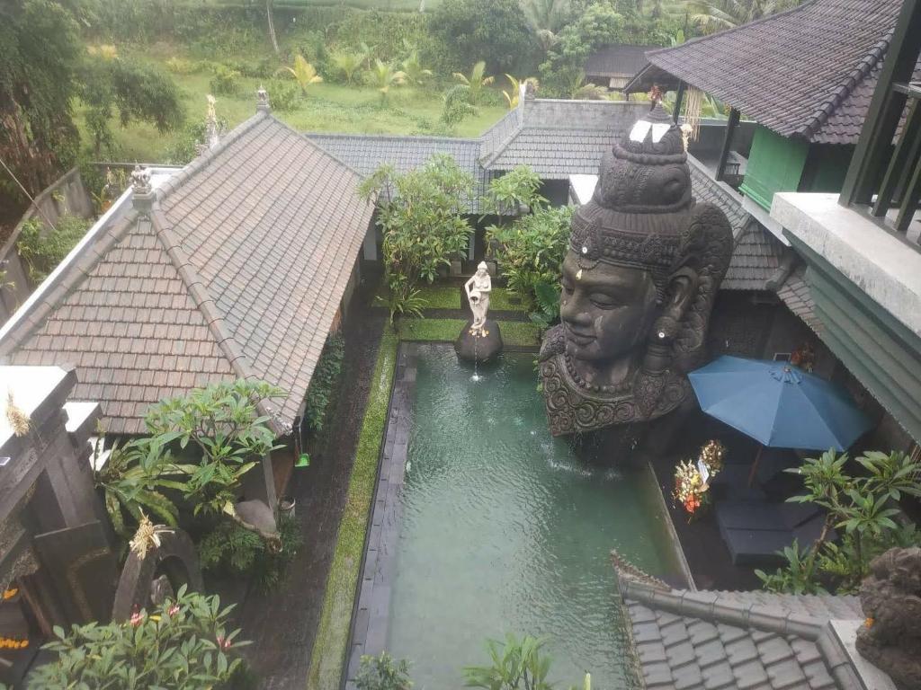 una vista aérea de un jardín con una estatua en el agua en Huts Rock Ubud en Ubud