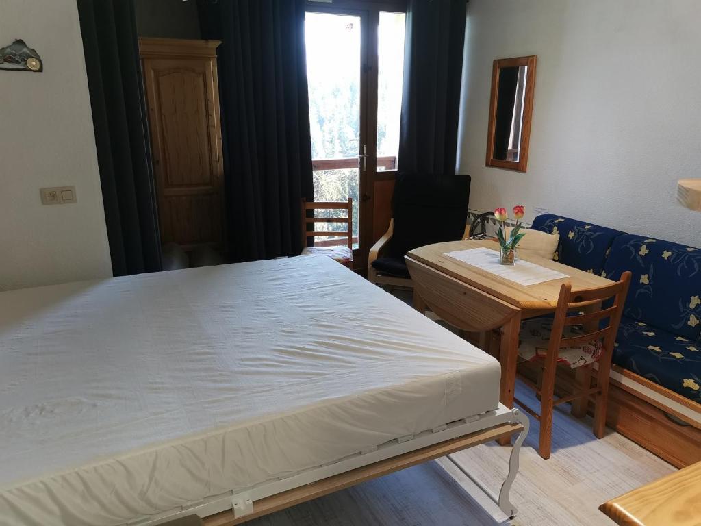 a bedroom with a bed and a table and a couch at Appartement Edelweiss Chamrousse vue sur Recoin La Croix de Chamrousse Grenoble in Chamrousse