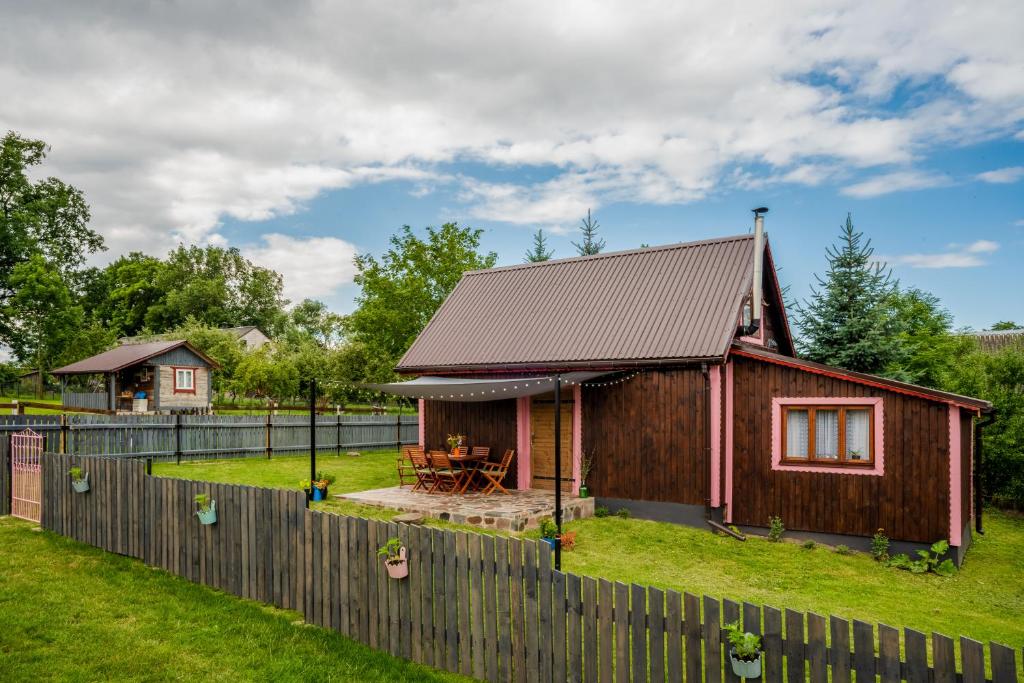 a small wooden house with a wooden fence at Alpakowo- Wolna Chata 20 in Drohiczyn nad Bugiem