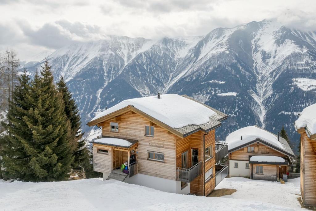 una cabaña de madera en la nieve con montañas en el fondo en Aarninkhof, en Bettmeralp