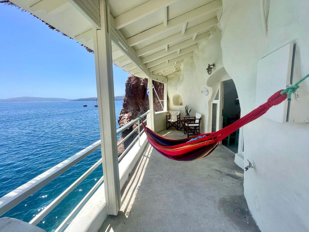 a hammock on the balcony of a house overlooking the ocean at Mermaid Cave Apartment Old Port, Fira in Fira