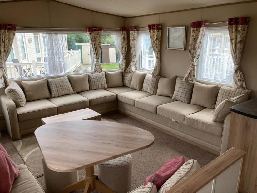 un soggiorno con divano e tavolo di Deluxe 3 Bedroom Caravan with extra en-suite North Shore a Skegness