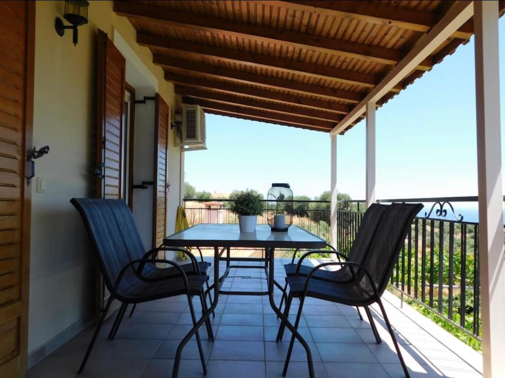 patio con mesa y sillas en el balcón en Nirvana Guest House, en Vasilítsion