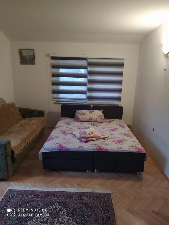 um pequeno quarto com uma cama e um sofá em Apartman Mickey em Sarajevo