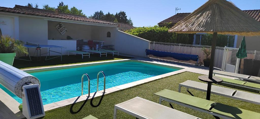 a swimming pool with chairs and an umbrella next to a house at Gites de la Casasole in Vogüé