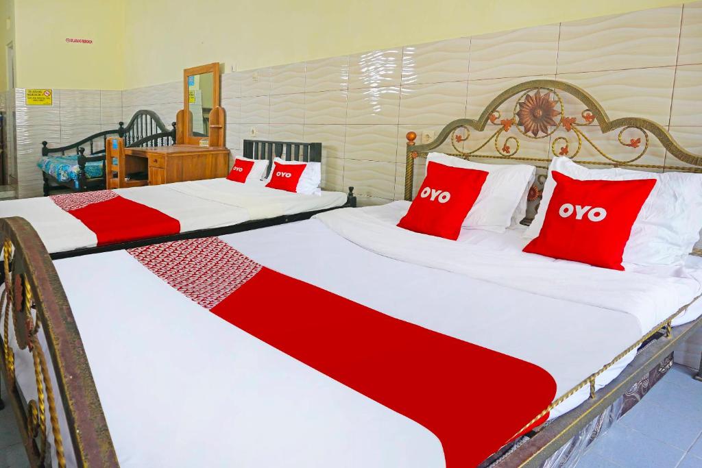 OYO 91411 Putih Mulia Homestay Syariah في Lumajang: سريرين في غرفة مع وسائد حمراء وبيضاء