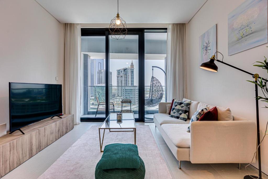 ein Wohnzimmer mit einem Sofa und einem TV in der Unterkunft Magnificent apartment in Address Beach Residence, 1 BR, the 6th floor in Dubai