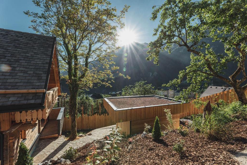 een tuin met een houten hek met de zon op de achtergrond bij Xeishittn VogelNest in Hieflau