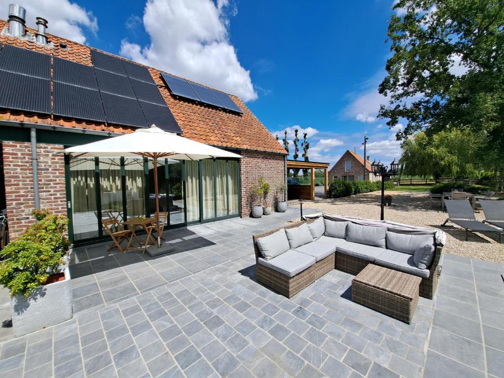 eine Terrasse mit einem Sofa und einem Sonnenschirm in der Unterkunft Rêveries in Roeselare
