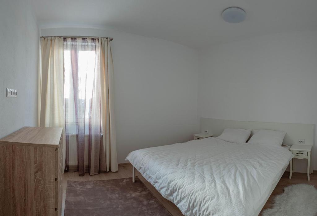 a bedroom with a white bed and a window at Solomon Apartments Ap 3 in Sângeorgiu de Mureș