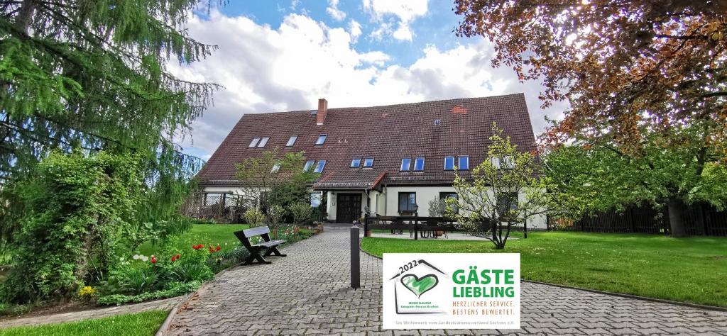 a sign in front of a house with a building at Pension Am Kirschberg in Bannewitz