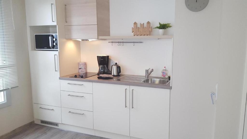 a white kitchen with a sink and a refrigerator at Résidence Séniors Domitys Les Hautes Feuilles in Reims