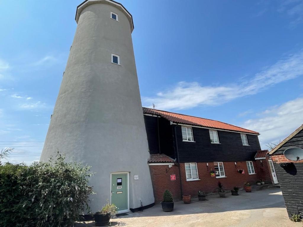 a lighthouse next to a building with a black house at Yaxham Mill in East Dereham