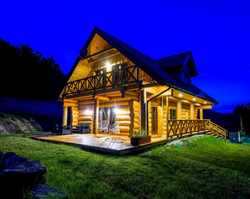 eine Blockhütte mit einer Terrasse in der Nacht in der Unterkunft Chata Czego Dusza Pragnie in Zachełmie