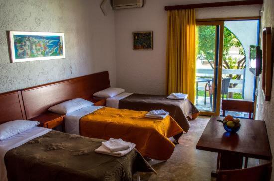 una camera d'albergo con tre letti e un tavolo di ResidenceTheo a Selianitika