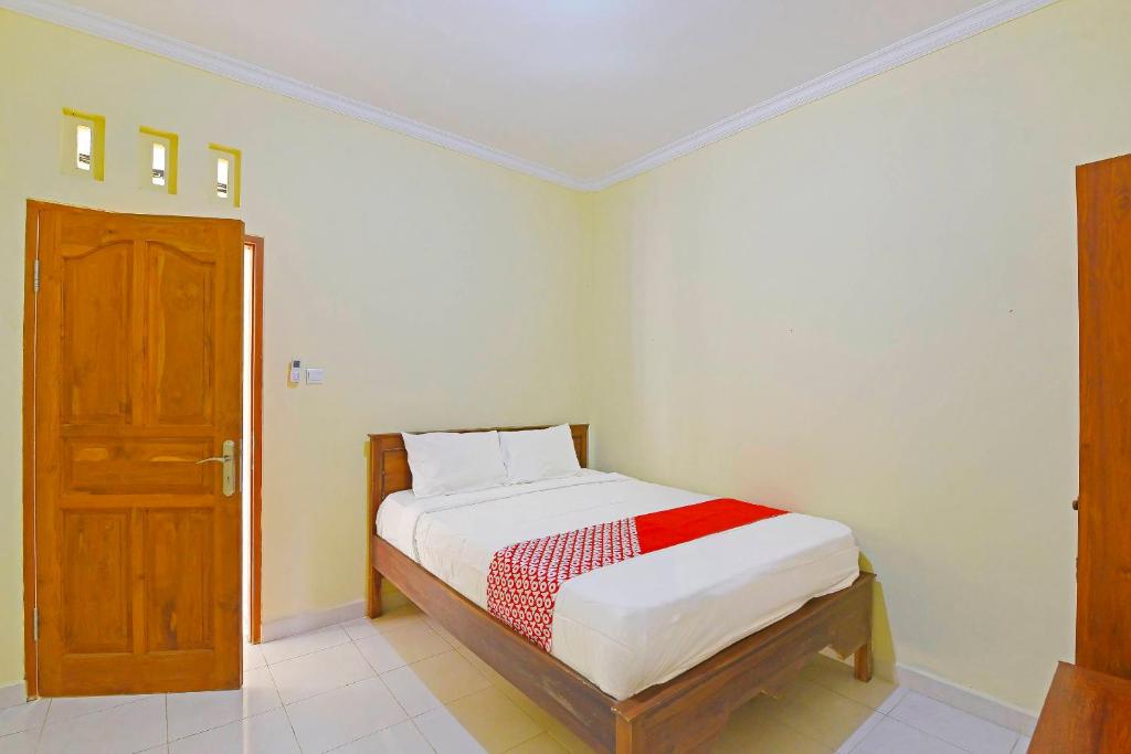 ein kleines Schlafzimmer mit einem Bett und einer Holztür in der Unterkunft OYO Life 90675 Ld Residence in Ungasan