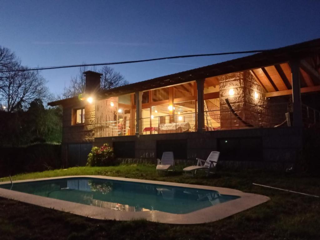 una casa con piscina por la noche en Lobetios - Casa rural en Santiago