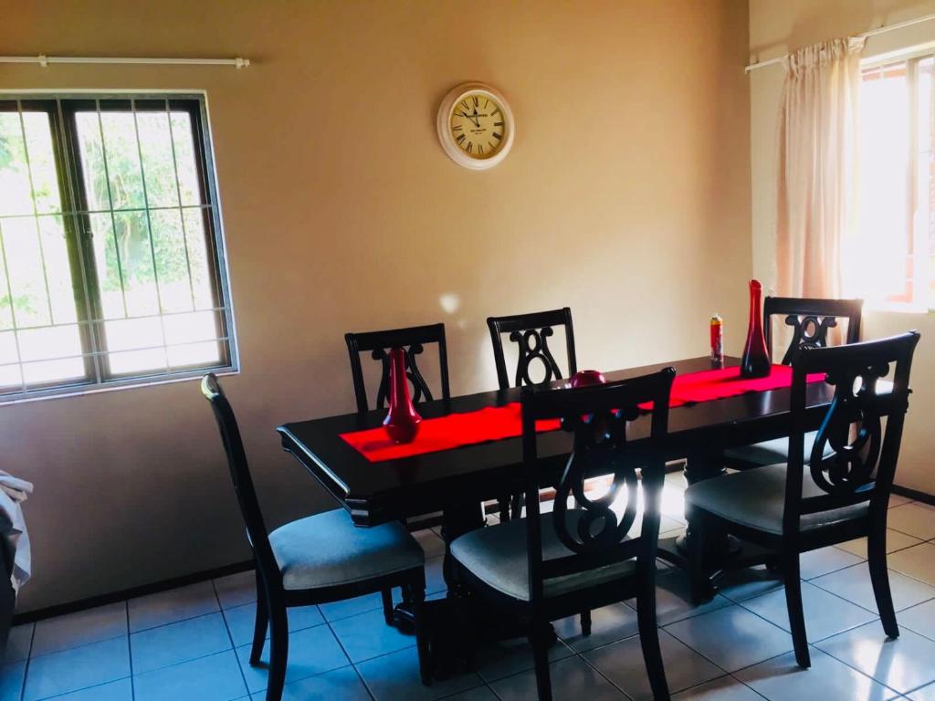 a dining room table with four chairs and a clock on the wall at Devine Stay- Margate in Margate